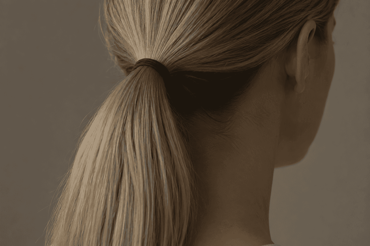 A close view of hair gathered into a low, tightly tied ponytail at the nape of the neck.